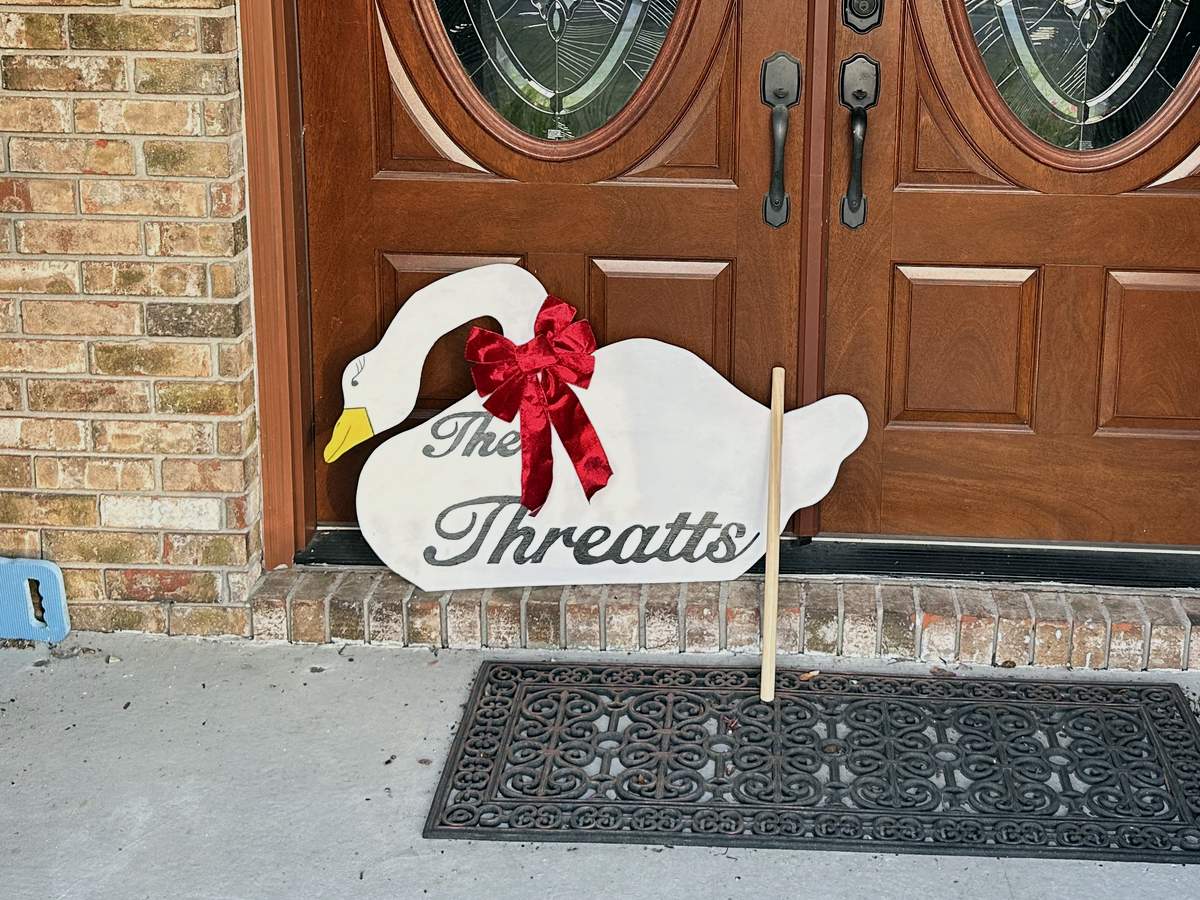 A finished Christmas goose with a red velvet bow on a front porch